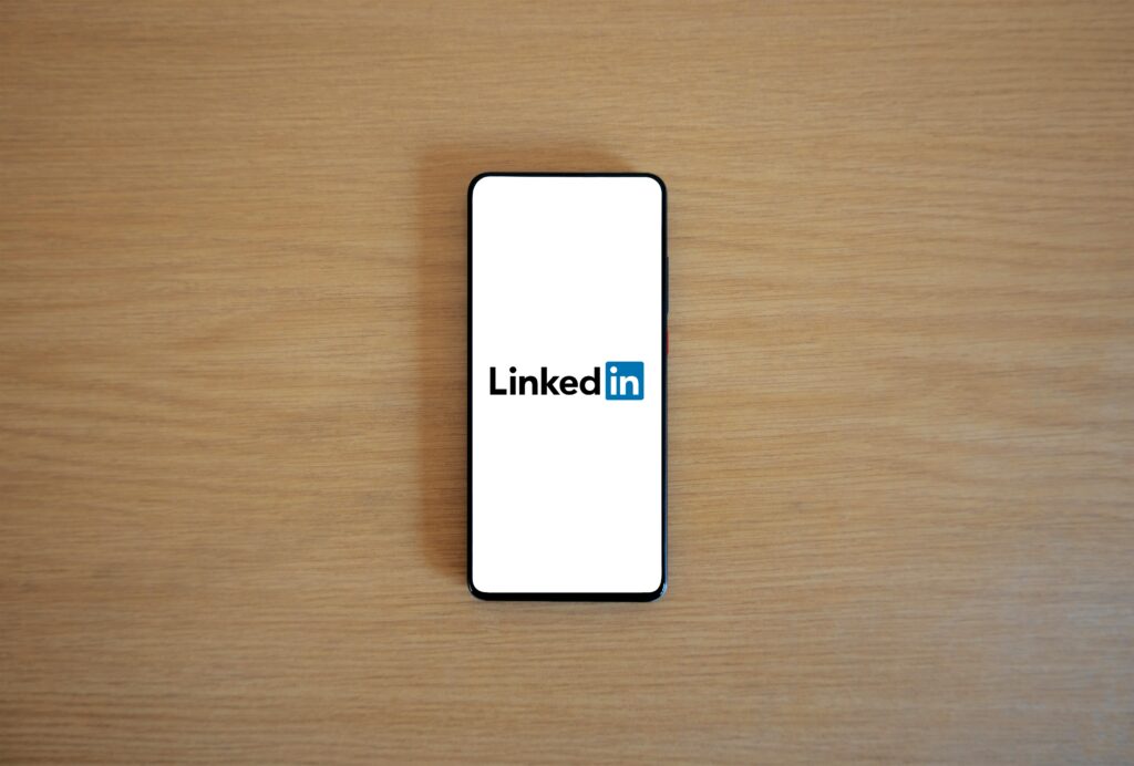 pexels-photo-20716646-20716646 Top view of a smartphone displaying the LinkedIn logo on a wooden surface.