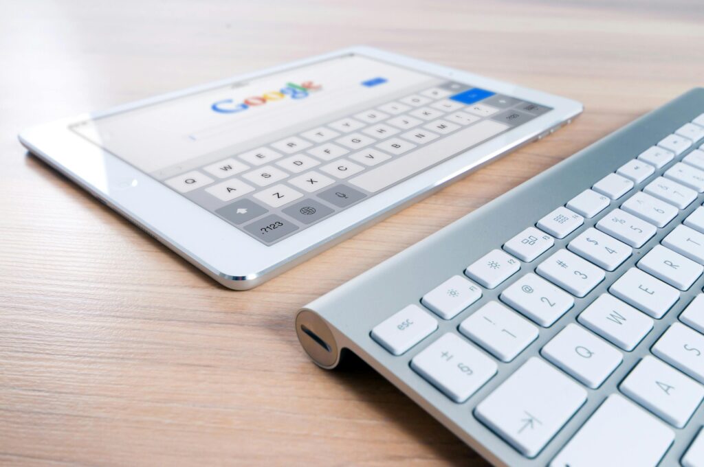 pexels-photo-270669-270669-1 A modern tablet displaying a search engine logo next to a wireless keyboard on a wooden desk.